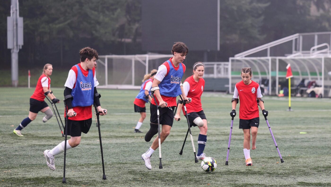 Amputee soccer players, wearing red UASA jerseys and blue pinnies, take part in a scrimmage.