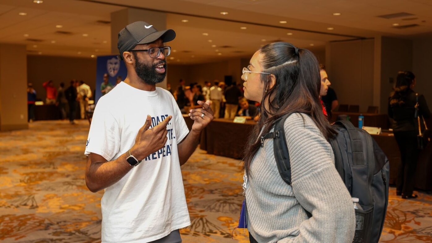Michel Tume speaks to a young attendee at a sports tourism event