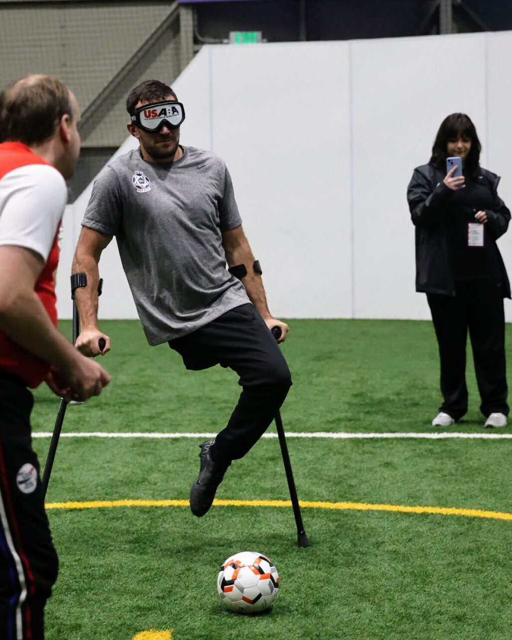 Nico Calabria, captain of the U.S. Amputee Soccer Men's National Team, tries out Blind Soccer, wearing a visor, coached by a Blind Soccer player