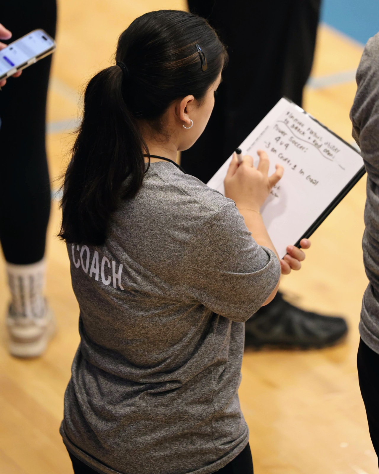 Jasela, a dwarf soccer for the U.S. Women's National Team, holds up a clipboard as she prepares to lead a coaching session