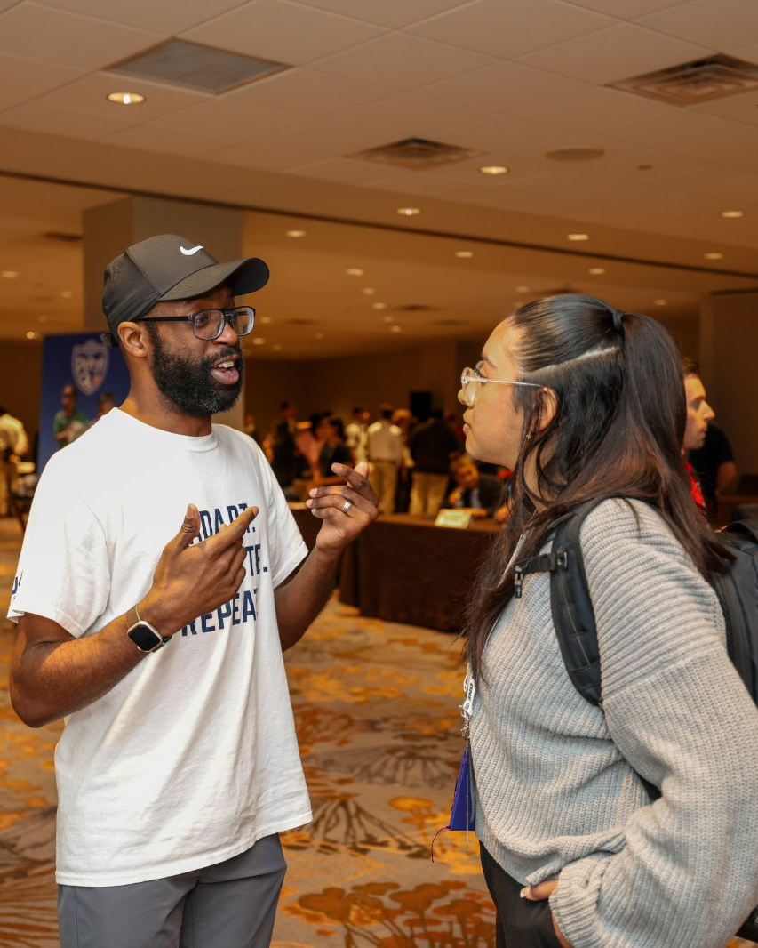 Michel Tume speaks to a young attendee at a sports tourism event
