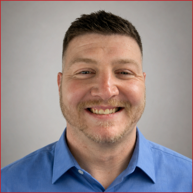 Justin Hauser smiles to the camera, wearing a blue shirt